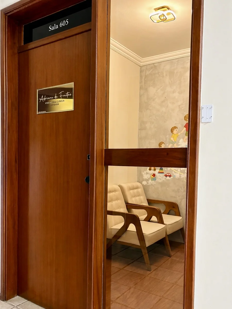 Porta da sala 605 e a sala de espera com duas poltronas